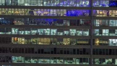 İş kulesi binasının gece ön cephesinde ışık zamanlaması olan bir sürü pencere var. Her pencerede hayat var. Bir ofis gökdeleninin cam cephesinin havadan görünüşü.
