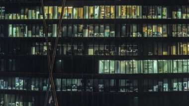 Kule binasının ön cephesinde, ışık zamanlaması olan bir sürü pencere var. Her pencerede hayat var. Finans bölgesinde bir ofis gökdelenin cam cephesinin havadan görünüşü.