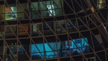 Kule binalarının ön cephesinden gece görüş açısı ve ışık zamanlaması olan bir sürü pencere. Her pencerede hayat var. Yerleşim yeri gökdelenlerinin cam cephesinin havadan görünüşü.