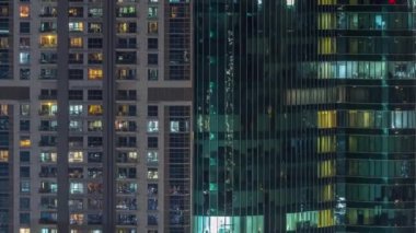 Ofis ve konutların pencereleri gece vakti aydınlatılıyor. Cam mimari, şirket binası, parlayan ışıklar.