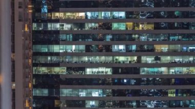 Ofis binalarının camları gece saatlerinde aydınlatılıyor. Cam mimari, şirket binası, parlayan ışıklar.