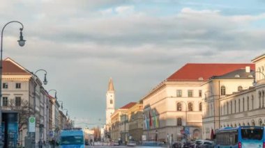 Ludwigstrasse ve St.Ludwig Kilisesi Odeonsplatz zaman diliminden. Gün batımında birçok araba ve otobüsle kavşakta trafik vardı. Münih, Almanya