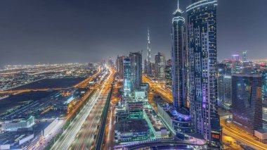 Dubai, Bae'de şeyh zayed yol gece timelapse modern gökdelenler ve trafik ile Akşam silueti. Işıklı iş koyu mimarisinin havadan görünümü.