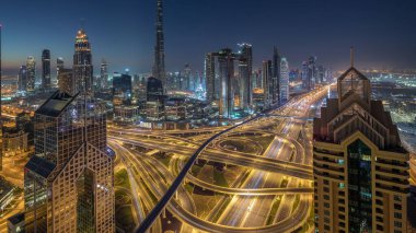 Dubai şehir merkezi silueti en yüksek gökdelenler ve karayolu kavşak gece gündüz geçiş timelapse üzerinde en işlek trafik ile. Yukarıdan havadan görünüm