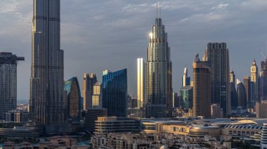Dubai Şehir Merkezi 'nin ufuk çizgisi gün batımından gece saatlerine kadar Dubai, Birleşik Arap Emirlikleri' nin tepesinden panoramik manzaralı kulelerle dolu. Güneş gökdelenden yansıyor. Çember yollarda ve çeşmelerde trafik