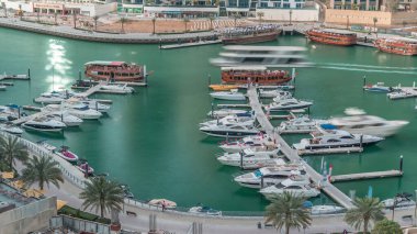 Dubai Marina körfezindeki iskeleye park etmiş lüks yatlar. Şehir hava manzaralı zaman ayarlı. Gezinti geçidi etrafında