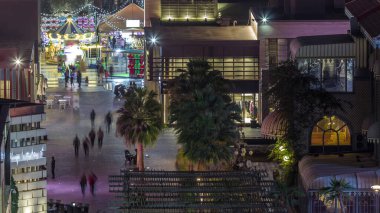 Dubai, Bae'de gece saatlerinde ışıklı binalarla Jbr'de yürüyen turistlerin havadan görünümü. Birçok aktivite ve ilgi çekici yer, mağazalar ve restoranlar ile rıhtım