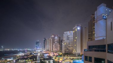 Dubai, Bae arka plan gece timelapse ışıklı gökdelenler ile Jbr yürüyüş plaj ve turistlerin havadan görünümü. Birçok aktivite ve ilgi çekici yer, mağazalar ve restoranlar ile rıhtım