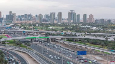 Dubai Golf Sahası 'nın arka plan hava gününden geceye geçiş zamanlarında yeşillik ve tekom bölgelerinden oluşan bir manzarası var. Şeyh zayed yolunda trafik kesişiyor.