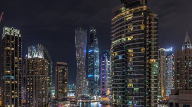 Dubai Marina 'daki çeşitli gökdelenlerin ve kulelerin görüntüsü. Kentsel ufuk çizgisinde aydınlatılmış modern binalar