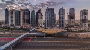 Dubai Marina 'dan gün doğumunda Şeyh Zayed yoluna giden hava manzaralı Jlt gökdelenleri zaman ayarlı, Dubai. Trafik ve metro istasyonu. Turuncu bulutlu gökyüzü. Birleşik Arap Emirlikleri