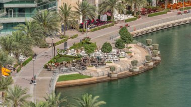 Dubai Marina Havaalanı 'nda bir restoranı olan bir rıhtım gezisi. Kanalda yüzen tekne ve yatlar. Dubai, Birleşik Arap Emirlikleri