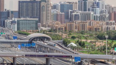 Dubai Golf Sahası 'nın arka planında yeşil ve tekom bölgelerinden oluşan bir şehir manzarası var. Şeyh zayed yolunda kavşak ve metro istasyonu trafiği