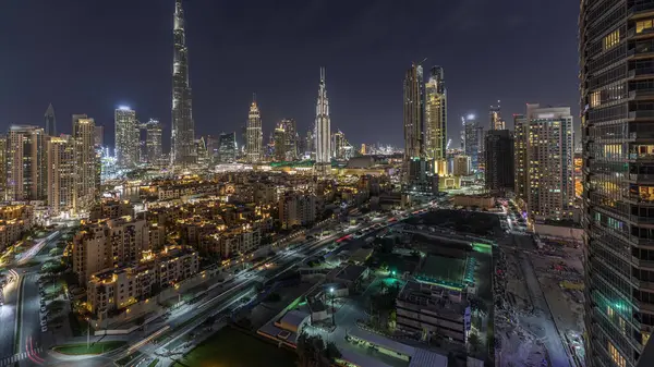 Dubai Downtown skyline night with Burj Khalifa and other towers panoramic view from the top in Dubai, United Arab Emirates. Traffic on circle road and fountains. Traditional and modern buildings.