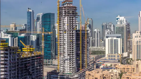 Construction activity in Dubai downtown with cranes and workers timelapse, UAE. Building of new skyscrapers and towers near business bay