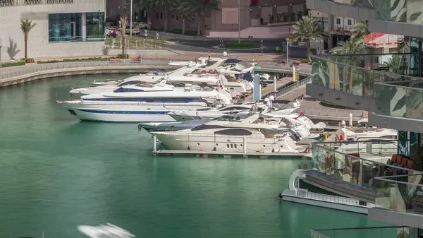 Dubai Marina Limanı 'ndaki rıhtım güvertesi, zaman ayarlı. Kanalda yüzen tekne ve yatlar. Dubai, Birleşik Arap Emirlikleri