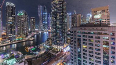 Dubai Marina yerleşim yerlerinin ve gökdelenlerin panoramik hava manzarası ve rıhtıma bakan gece saatleri. Yüzen tekneler ve yatlar