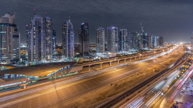 Dubai Marina 'dan Şeyh Zayed yoluna giden hava panoramik manzaralı Jlt aydınlatmalı gökdelenler, gece zaman çizelgesi, Dubai. Trafik, köprüler ve metro hattı. Birleşik Arap Emirlikleri