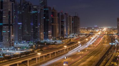 Dubai Marina 'dan Şeyh Zayed yoluna gece gündüz aydınlık gökdelenlerle geçiş zamanı, Dubai. Trafik, köprüler ve metro istasyonu. Birleşik Arap Emirlikleri