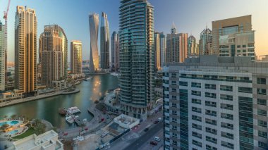 Dubai Marina yerleşim ve ofis gökdelenlerinin deniz manzarası. Gün doğumundan sonraki sabah gölgeler hızla hareket ediyor. Güneş camdan yansıyor. Yüzen tekneler ve yatlar