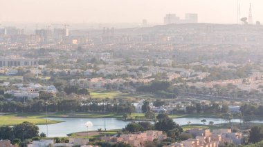 Yeşil çim ve göller timelapse ile Golf sahası ile villa ve evlere havadan görünümü. Sokaklardatrafik. Sıcak akşam ışığı