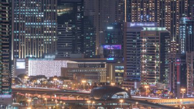 Dubai Marina, Dubai, Birleşik Arap Emirlikleri'nde gece saatlerinde gökdelenleri ve golf sahalarını aydınlatmaktadır. Şeyh zayed yol ve metro istasyonu üzerinde trafik ile Greens ilçesinden havadan görünümü