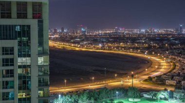 Greens semtinin havadan görünümü, villalar ve Golf sahası ile evler gece zaman aşımına uğrar. Kavşaktaki trafik. Parlayan pencereleri olan konut binaları