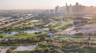 Golf sahası ve Jumeirah göl kuleleri gökdelenler gün batımı ndan önce timelapse, Dubai, Birleşik Arap Emirlikleri. Yeşiller bölgesinden havadan görünüm.