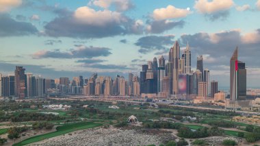 Dubai Marina skyscrapers and golf course morning timelapse, Dubai, United Arab Emirates. Aerial view from Greens district. Green lawn and cloudy sky clipart