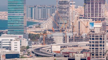 Dubai media city skyscrapers and construction site on palm jumeirah timelapse, Dubai, United Arab Emirates. Aerial view from Greens district with traffic on the road clipart