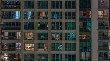 Çok katlı binanın parlayan pencereleri içinde aydınlatma ve daireler timelapse insanlar hareketli. Dubai yeşiller bölgesinde modern konut gökdelenler havadan görünümü