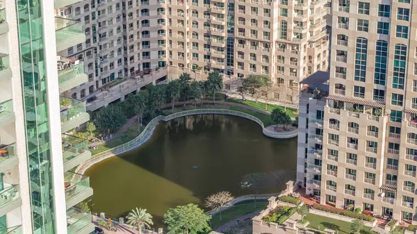 Manmade lake and residential buildings in Greens neighborhood timelapse in Dubai, UAE. Aerial view from above