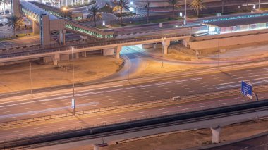 Dubai, Bae Dubai Marina gece timelapse tramvay durağıile alışveriş merkezi yakınında trafik havadan üst görünümü. Yanıp sönen ışıklar ve yolda trafik ile Aydınlatılmış modern kuleleri