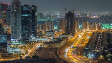 Jumeirah Lake Towers yerleşim bölgesi Dubai Marina yakınında hava gece timelapse. Işıklı modern gökdelenler ve yukarıdan trafik