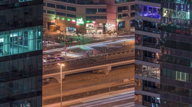 Dubai marina ve Jlt gökdelenler hava gece timelapse, Dubai, Birleşik Arap Emirlikleri ile kavşakta trafiğe çatı görünümü. Yukarıdan ışıklı kuleler