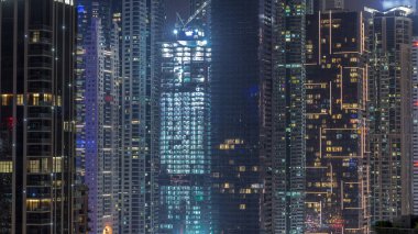 Dubai Marina 'daki çeşitli gökdelenlerin ve kulelerin görüntüsü. Kentsel ufuk çizgisinde inşaat alanı ile aydınlatılmış modern binalar