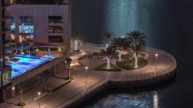 Dubai Marina hava sahasında palmiyeler daireler çizerek rıhtımda geziniyor. Kanalda yüzen tekne ve yatlar. Dubai, Birleşik Arap Emirlikleri