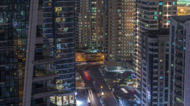 Dubai Marina 'daki çeşitli gökdelenlerin ve kulelerin görüntüsü. Kentsel gökdelendeki aydınlanmış modern binalar ve caddelerde trafik