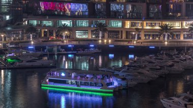 Dubai Marina Limanı 'ndaki rıhtım güvertesi gece uçuşları. Kanalda yüzen tekne ve yatlar. Dubai, Birleşik Arap Emirlikleri
