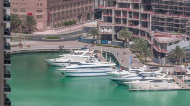 Dubai Marina Limanı 'ndaki rıhtım güvertesi, zaman ayarlı. Kanalda yüzen tekne ve yatlar. Dubai, Birleşik Arap Emirlikleri