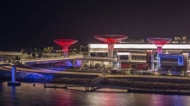 Dubai'deki Bluewaters Adası'nda ışıklı binalarla gece saati. Yatlar ve tekneler geçiyor. Jumeirah Beach Residence kıyılarında bulunan insan yapımı ada