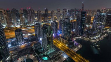 Dubai Marina gece gündüz geçiş timelapse havadan üst görünümü. Dubai, Bae gün doğumundan önce yüzen yatlar ve tekneler ile gezinti ve kanal. Işıklı modern kuleler ve yolda trafik