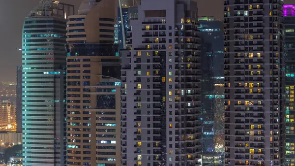 Residential and office buildings in Jumeirah Lake Towers aerial night timelapse in Dubai, UAE. Illuminated skyscrapers with lights in windows
