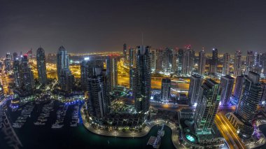 Dubai Marina gece gündüz geçiş timelapse havadan üst görünümü. Dubai, Bae gün doğumundan önce yüzen yatlar ve tekneler ile gezinti ve kanal. Işıklı modern kuleler ve yolda trafik