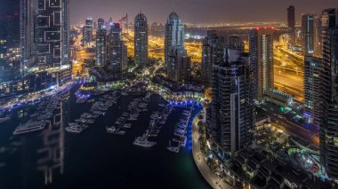 Dubai Marina gece gündüz geçiş timelapse havadan üst görünümü. Dubai, Bae gün doğumundan önce yüzen yatlar ve tekneler ile gezinti ve kanal. Işıklı modern kuleler ve yolda trafik