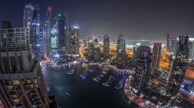 Dubai Marina gece geçiş timelapse havadan üst görünümü. Dubai, Bae yüzen yatlar ve tekneler ile gezinti ve kanal. Işıklı modern kuleler ve yolda trafik