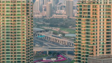 Dubai internet şehri yakınlarındaki metro istasyonu ve Dubai Media City bölgelerinin yanı sıra golf kulübü akşamları. Dubai marinasından hava manzaralı ve otoyolda trafik var. Arkaplanda yeşiller ve tekom bölgesi