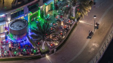 Dubai Marina Cafe ve Restaurant ile modern set gece timelapse. Masalar ve insanlar sandalyeler üzerinde oturan ile Kaldırım havadan üst görünümü