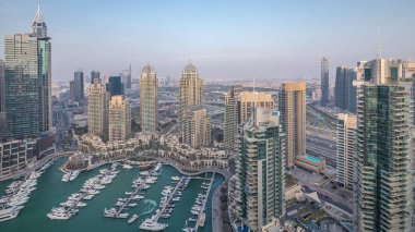 Dubai Marina'nın havadan üstten gündüz geceye geçiş saati. Dubai, Bae gün batımından sonra yüzen yatlar ve tekneler ile gezinti ve kanal. Işıklı modern kuleler ve yolda trafik