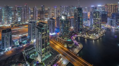 Dubai Marina gece timelapse havadan üst görünümü. Dubai, Bae yüzen yatlar ve tekneler ile gezinti ve kanal. Işıklı modern kuleler ve yolda trafik